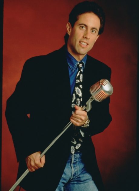 Jerry Seinfeld holding a microphone.