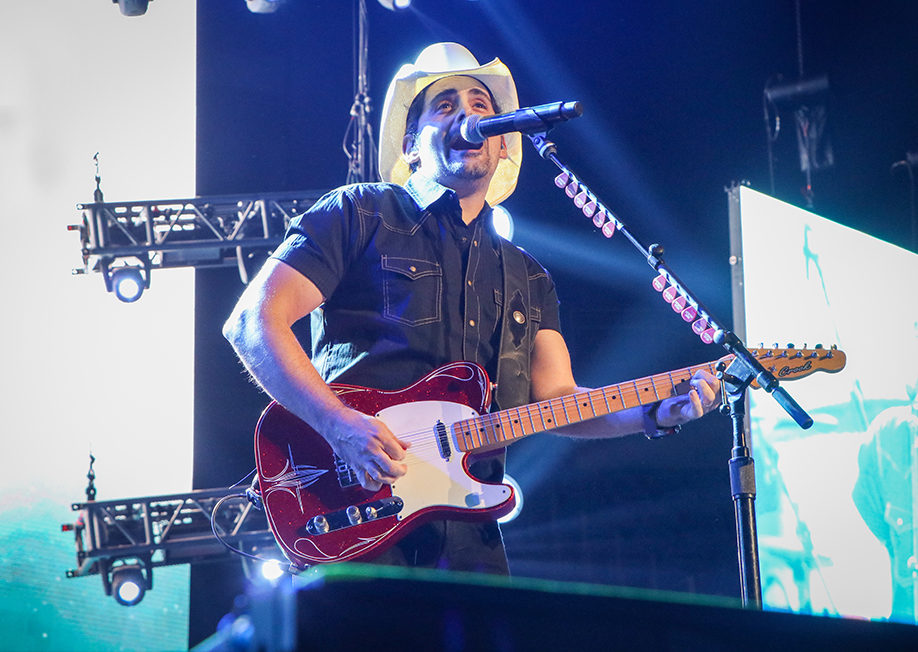 Booking National Entertainment Brad Paisley on stage with a guitar wearing a cowboy hat and singing.